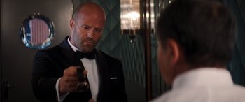 Movie still from “Operation Fortune: Ruse de Guerre” (2023), directed by Guy Ritchie – A bald man in a tuxedo looking at his reflection in a mirror; Close Up shot, Over the shoulder angle