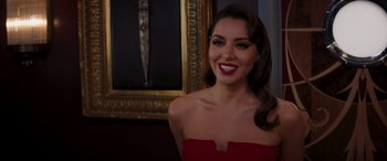 Movie still from “Operation Fortune: Ruse de Guerre” (2023), directed by Guy Ritchie – A woman in a red dress posing in front of a painting; Close Up shot, Over the shoulder angle