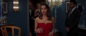 Movie still from “Operation Fortune: Ruse de Guerre” (2023), directed by Guy Ritchie – A woman in a red dress holding a glass of wine; Medium shot, Over the shoulder angle