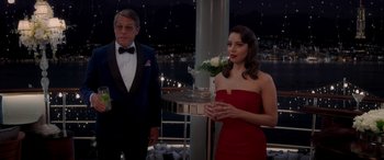 Movie still from “Operation Fortune: Ruse de Guerre” (2023), directed by Guy Ritchie – A woman in a red dress holding a tray of flowers; Medium shot, Over the shoulder angle