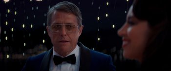 Movie still from “Operation Fortune: Ruse de Guerre” (2023), directed by Guy Ritchie – A person wearing glasses and a bow tie; Close Up shot, Over the shoulder angle