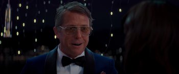 Movie still from “Operation Fortune: Ruse de Guerre” (2023), directed by Guy Ritchie – A person wearing a suit and bow tie; Close Up shot, Over the shoulder angle