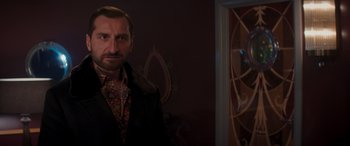 Movie still from “Operation Fortune: Ruse de Guerre” (2023), directed by Guy Ritchie – A person wearing a suit and tie; Medium shot, Low angle