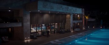 Movie still from “Operation Fortune: Ruse de Guerre” (2023), directed by Guy Ritchie – Two people are walking in front of a building at night; Extreme Wide shot, High angle