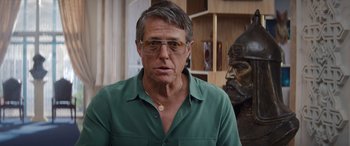 Movie still from “Operation Fortune: Ruse de Guerre” (2023), directed by Guy Ritchie – A person wearing glasses and a green shirt; Close Up shot, Low angle