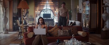 Movie still from “Operation Fortune: Ruse de Guerre” (2023), directed by Guy Ritchie – A man and a woman sitting in a living room with a computer; Wide shot, Over the shoulder angle
