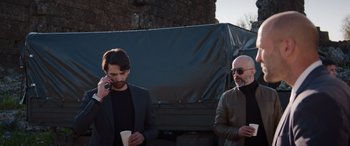 Two men standing next to each other while one of them is holding a cup