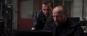 Movie still from “Operation Fortune: Ruse de Guerre” (2023), directed by Guy Ritchie – Two men looking at a computer screen; Close Up shot, Low angle