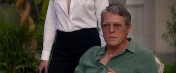 Movie still from “Operation Fortune: Ruse de Guerre” (2023), directed by Guy Ritchie – A person wearing glasses and a green shirt; Close Up shot, Over the shoulder angle