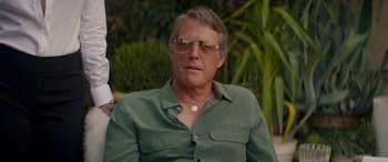 Movie still from “Operation Fortune: Ruse de Guerre” (2023), directed by Guy Ritchie – A person wearing sunglasses and a green shirt; Close Up shot, Over the shoulder angle