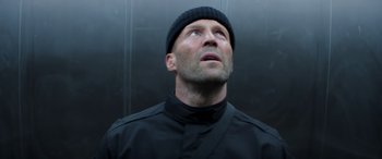 Movie still from “Operation Fortune: Ruse de Guerre” (2023), directed by Guy Ritchie – A man wearing a black shirt and a black hat looking up; Close Up shot, Low angle