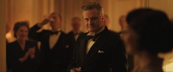Movie still from “Operation Mincemeat” (2021), directed by John Madden – A man in a tuxedo standing in front of a group of men; Medium shot, Low angle