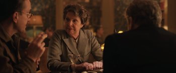 Movie still from “Operation Mincemeat” (2021), directed by John Madden – An older woman sitting at a table with a glass of wine; Close Up shot, Over the shoulder angle