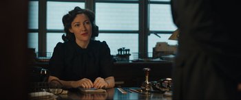 Movie still from “Operation Mincemeat” (2021), directed by John Madden – A woman sitting at a table in front of a window; Medium shot, Low angle