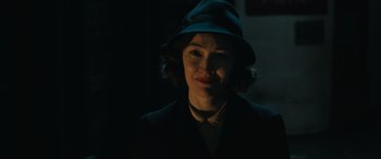 Movie still from “Operation Mincemeat” (2021), directed by John Madden – A woman wearing a hat in a dark room; Close Up shot, Over the shoulder angle