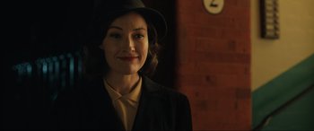 Movie still from “Operation Mincemeat” (2021), directed by John Madden – A woman wearing a hat and a suit; Close Up shot, Over the shoulder angle