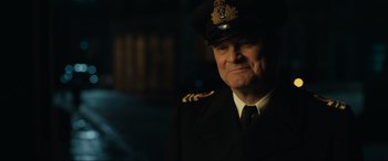 Movie still from “Operation Mincemeat” (2021), directed by John Madden – An older man wearing a uniform and a hat; Close Up shot, Over the shoulder angle