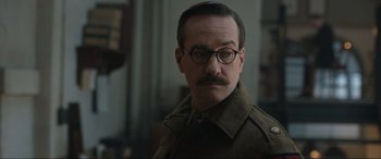 Movie still from “Operation Mincemeat” (2021), directed by John Madden – A man with a mustache wearing glasses and a coat; Close Up shot, Over the shoulder angle