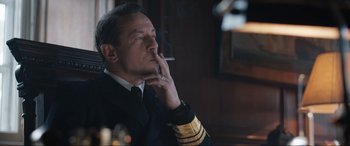 Movie still from “Operation Mincemeat” (2021), directed by John Madden – A man smoking a cigarette while wearing a uniform; Medium shot, Low angle