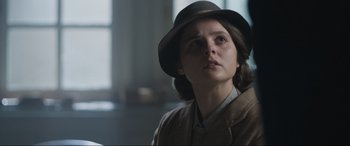 Movie still from “Operation Mincemeat” (2021), directed by John Madden – A woman wearing a hat and a jacket looking to her left; Close Up shot, Over the shoulder angle