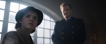 Movie still from “Operation Mincemeat” (2021), directed by John Madden – A man and a woman standing next to each other in front of a window; Close Up shot, Low angle
