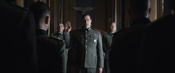Movie still from “Operation Mincemeat” (2021), directed by John Madden – A group of men in uniforms standing in a room; Medium shot, Over the shoulder angle