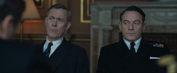 Movie still from “Operation Mincemeat” (2021), directed by John Madden – Two men in suits and ties standing next to each other; Medium shot, Low angle