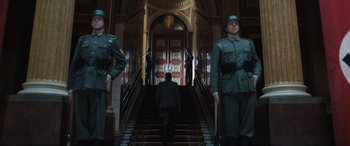 Movie still from “Operation Mincemeat” (2021), directed by John Madden – A group of men standing on top of a set of stairs; Wide shot, Low angle