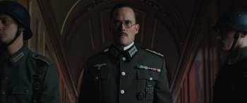 Movie still from “Operation Mincemeat” (2021), directed by John Madden – A man in a military uniform and glasses; Close Up shot, Low angle