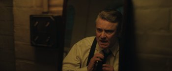 Movie still from “Operation Mincemeat” (2021), directed by John Madden – An older man is holding a tie in front of a mirror; Close Up shot, Low angle