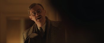 Movie still from “Operation Mincemeat” (2021), directed by John Madden – An old man with glasses and a beard wearing a suit and tie; Close Up shot, Over the shoulder angle