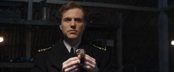 Movie still from “Operation Mincemeat” (2021), directed by John Madden – A man in a uniform holding a cell phone; Close Up shot, Low angle