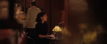 Movie still from “Operation Mincemeat” (2021), directed by John Madden – A woman sitting at a table with a glass of red wine; Medium shot, Over the shoulder angle