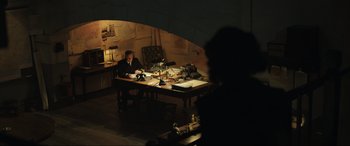 Movie still from “Operation Mincemeat” (2021), directed by John Madden – A man sitting at a desk in front of papers; Wide shot, Over the shoulder angle