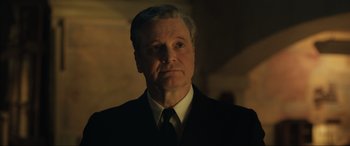 Movie still from “Operation Mincemeat” (2021), directed by John Madden – A person wearing a suit and tie; Close Up shot, Low angle