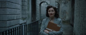 Movie still from “Operation Mincemeat” (2021), directed by John Madden – A woman in a gray suit holding a brown folder; Medium shot, Low angle