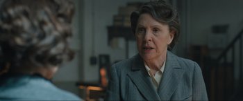 Movie still from “Operation Mincemeat” (2021), directed by John Madden – An older woman wearing a suit and a tie; Close Up shot, Over the shoulder angle