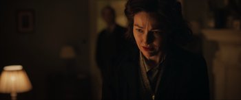 Movie still from “Operation Mincemeat” (2021), directed by John Madden – A woman in a dark room looking sad; Close Up shot, Over the shoulder angle
