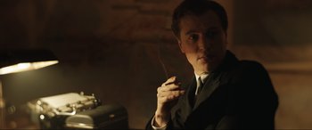 Movie still from “Operation Mincemeat” (2021), directed by John Madden – A man in a suit and tie smoking a cigarette; Close Up shot, Low angle