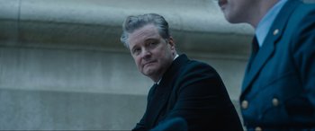 Movie still from “Operation Mincemeat” (2021), directed by John Madden – A person wearing a suit and tie; Close Up shot, Low angle