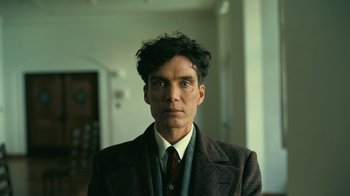 Movie still from “Oppenheimer” (2023), directed by Christopher Nolan – A man wearing a suit and tie in front of a mirror; Close Up shot, Low angle