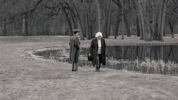Movie still from “Oppenheimer” (2023), directed by Christopher Nolan – Two men standing next to a body of water; Wide shot, Over the shoulder angle