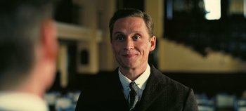 Movie still from “Oppenheimer” (2023), directed by Christopher Nolan – A person wearing a suit and tie; Close Up shot, Low angle