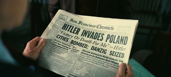Movie still from “Oppenheimer” (2023), directed by Christopher Nolan – A person holding up a newspaper with the headline hitler invades poland; Extreme Close Up shot, High angle