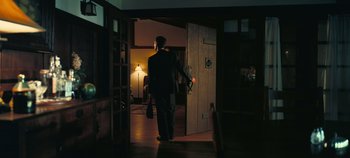 Movie still from “Oppenheimer” (2023), directed by Christopher Nolan – A man in a suit is walking through a room; Wide shot, Low angle