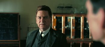 Movie still from “Oppenheimer” (2023), directed by Christopher Nolan – A person wearing a suit and tie; Close Up shot, Low angle