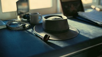 Movie still from “Oppenheimer” (2023), directed by Christopher Nolan – A hat and a smoking pipe on a table; Extreme Close Up shot, High angle
