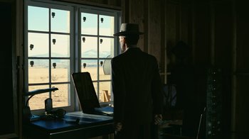 Movie still from “Oppenheimer” (2023), directed by Christopher Nolan – A man standing in front of an open window; Wide shot, Low angle