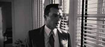 Movie still from “Oppenheimer” (2023), directed by Christopher Nolan – Black and white photograph of a man wearing a suit and tie; Close Up shot, Low angle