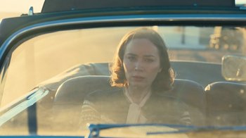 Movie still from “Oppenheimer” (2023), directed by Christopher Nolan – A woman sitting in the back seat of a car; Medium shot, Over the shoulder angle